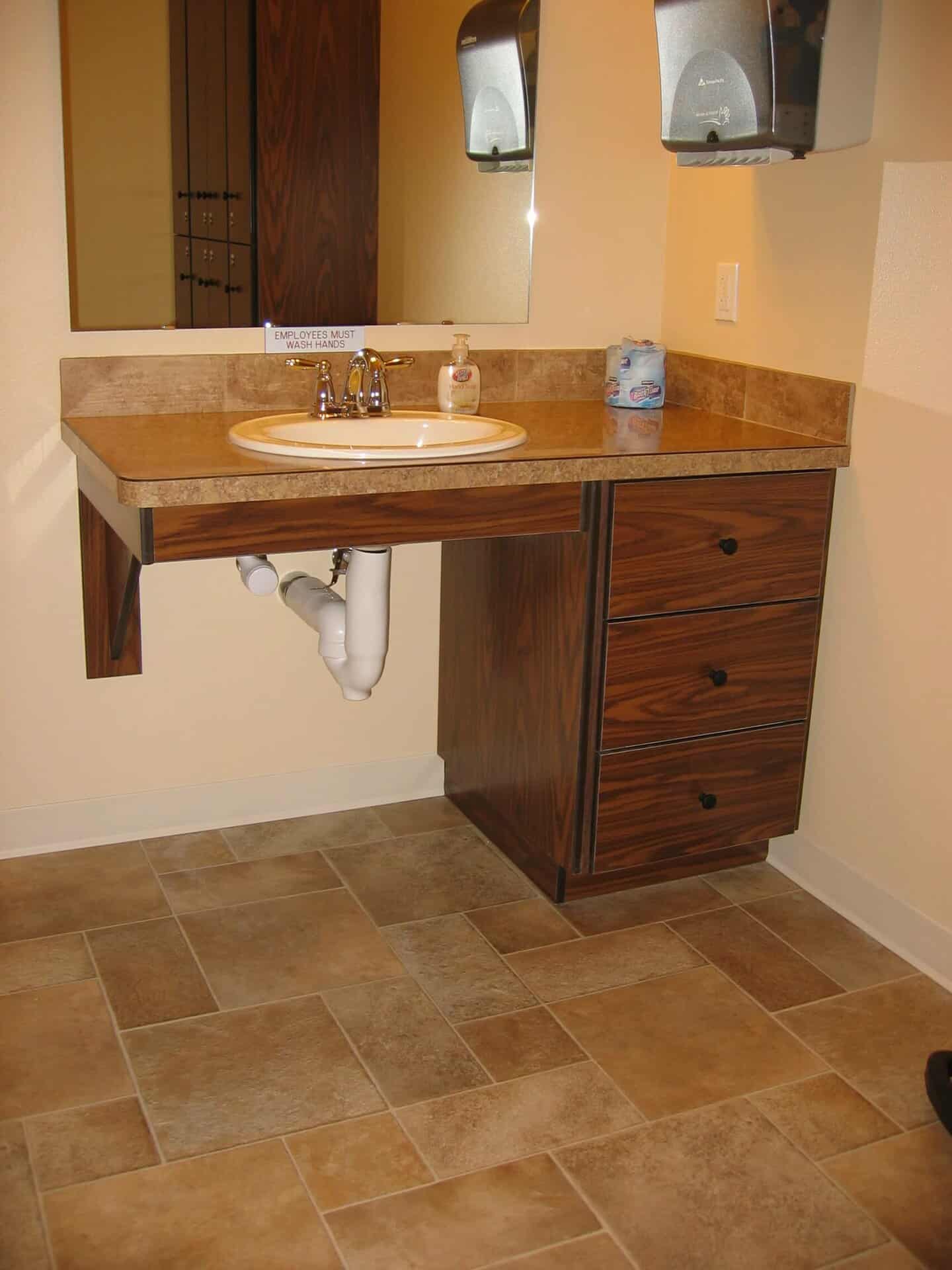 Picture of an office sink with ark wooden cabinets.
