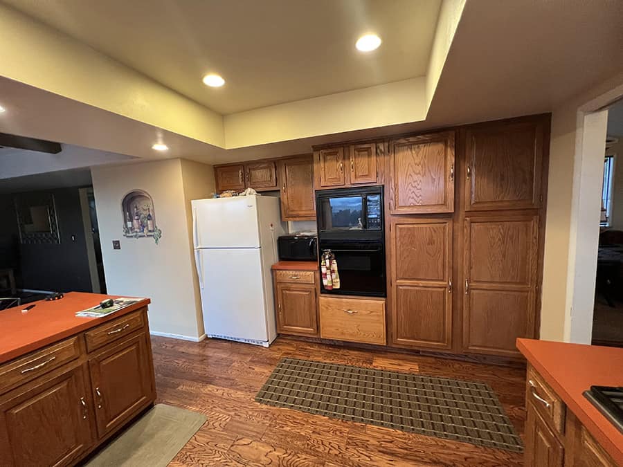 wood cabinets and dark walls with fridge and no island